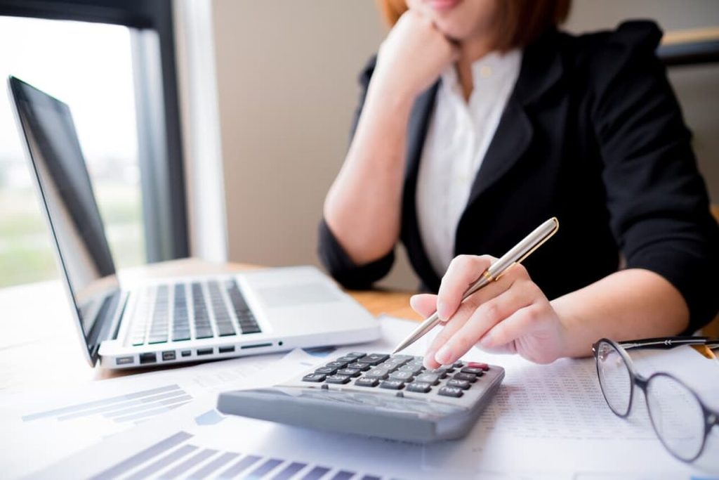 Mulher com calculadora na mesa e computador